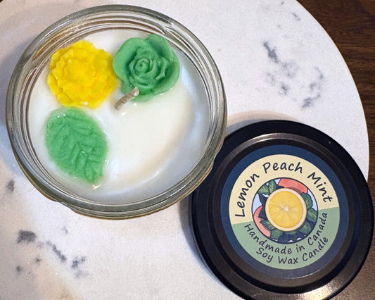 Lemon Peach Mint soy wax candle with decorative elements on a marble surface
