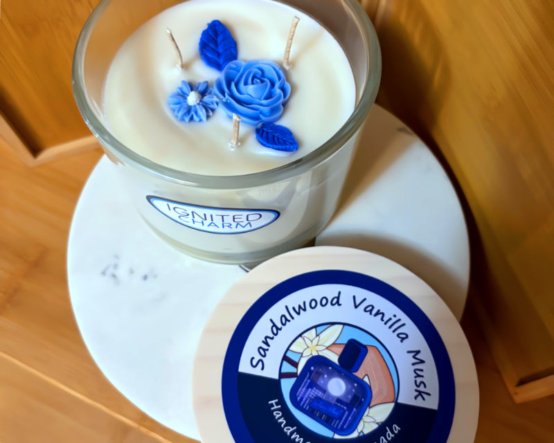 Candle with blue floral decorations and a visible brand label on a marble surface