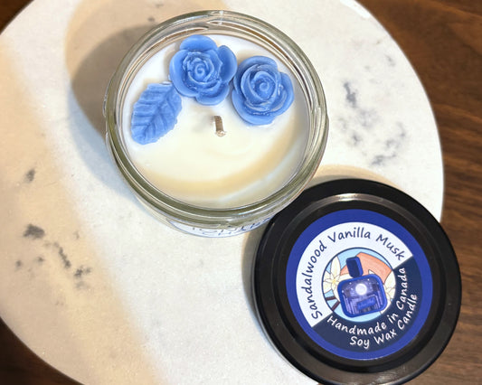Scented candle with blue floral decorations on a marble surface
