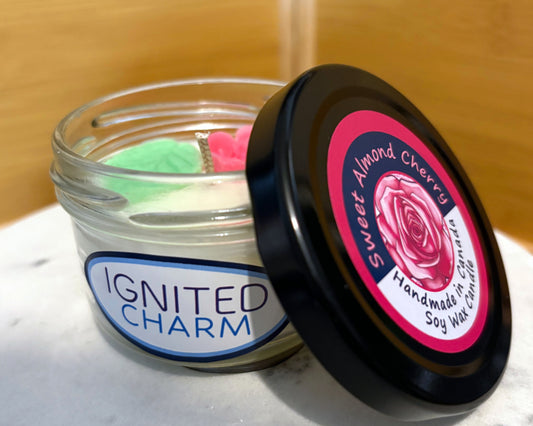 Jar of candle with 'Ignited Charm' label and jar lid with 'Sweet Almond Cherry' label.