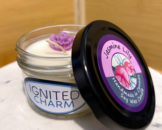 Scented candle jar with 'Ignited Charm' label and lid featuring floral design and text.