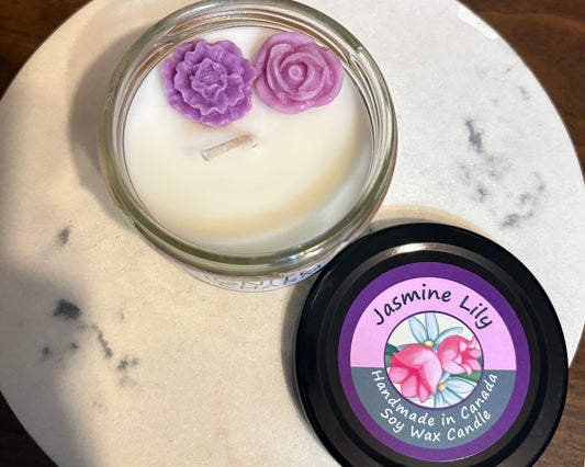 Candle with purple flower-shaped wick trimmer on a marble surface