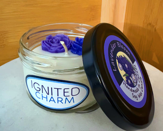 Candle jar with purple rose design and 'Ignited Charm' label against a wooden background